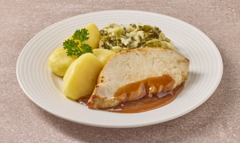 Gesneden varkensvlees in jus met savooiekool en gekookte aardappelen